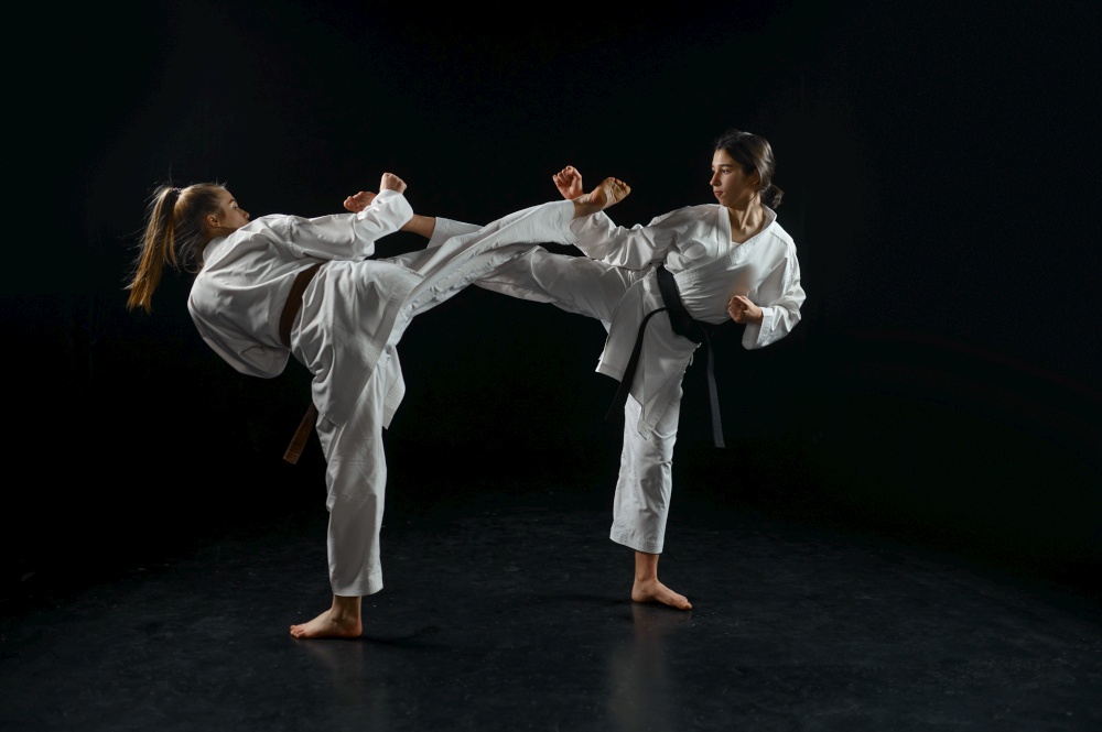 Female and male karate fighters, combat in action, white kimono, dark smoky background. Karateka on workout, martial arts, fighting competition. Female and male karate fighters, combat in action