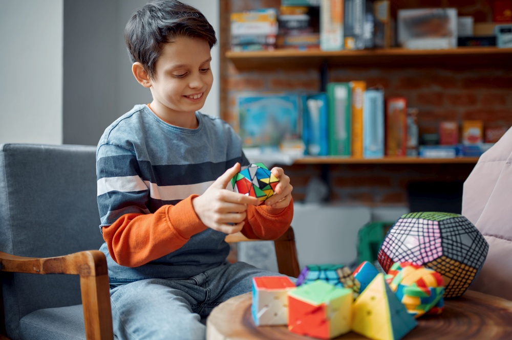 Young boy holds colorful puzzle cube in his hand. Toy for brain and logical mind training, creative game, solving of complex problems. Young boy holds colorful puzzle cube in his hand
