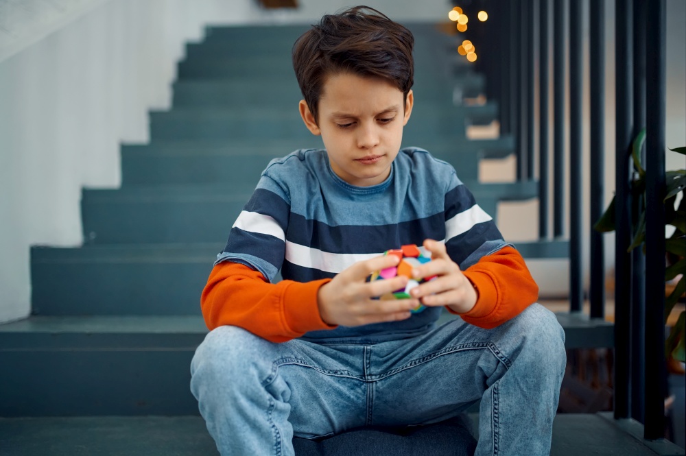 Thoughtful little boy play with puzzle cubes. Toy for brain and logical mind training, creative game, solving of complex problems. Thoughtful little boy play with puzzle cubes