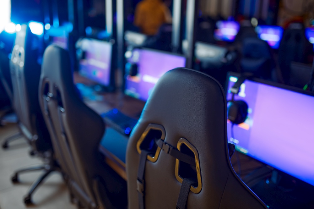 Row of monitors with headsets, gaming club interoir, nobody. Virtual entertainment, e-sport tournament, cybersport lifestyle. Internet cafe equipment. Row of monitors with headsets, gaming club, nobody