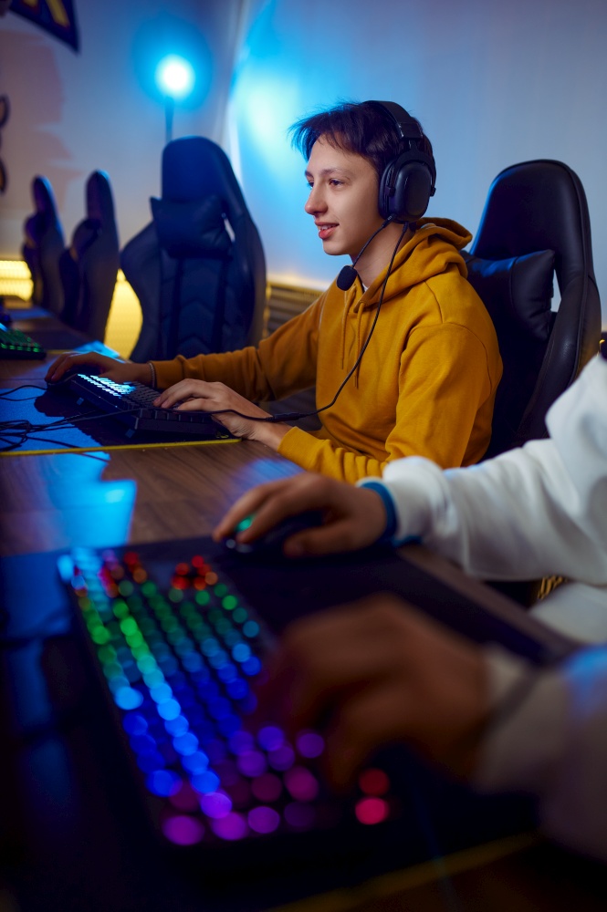 Two young gamers play in game club. Virtual entertainment, e-sport tournament, cybersport lifestyle. Male person leisures in internet cafe. Two young gamers play in game club