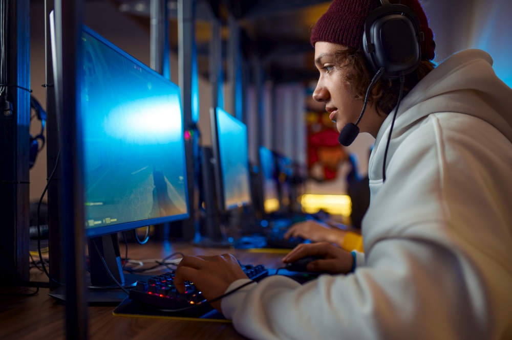 Two young gamers in headsets play in video game club. Virtual entertainment, e-sport tournament, cybersport lifestyle. Two young gamers in headsets play in video game club