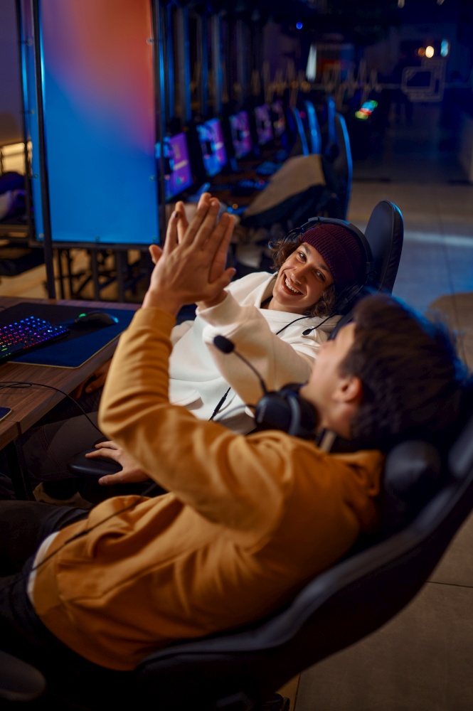 Two young gamers having fun in video game club. Virtual entertainment, e-sport tournament, cybersport lifestyle. Male person leisures in internet cafe. Two young gamers having fun in game club