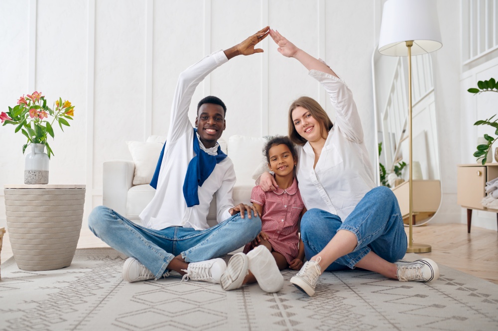 Happy family sitting on the floor in living room. Mother, father and their daughter poses at home together, good relationship. Happy family sitting on the floor in living room