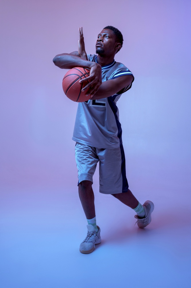 Strong basketball player hand holds ball in studio, neon background. Professional male baller in sportswear playing sport game.. Strong basketball player hand holds ball