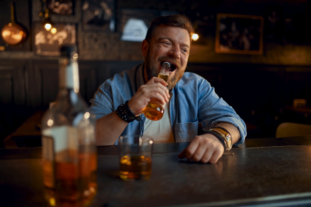 Man opens bottle of beer with his teeth at the counter in bar. One male person resting in pub, human emotions, leisure activities, nightlife. Man opens bottle of beer with his teeth in bar