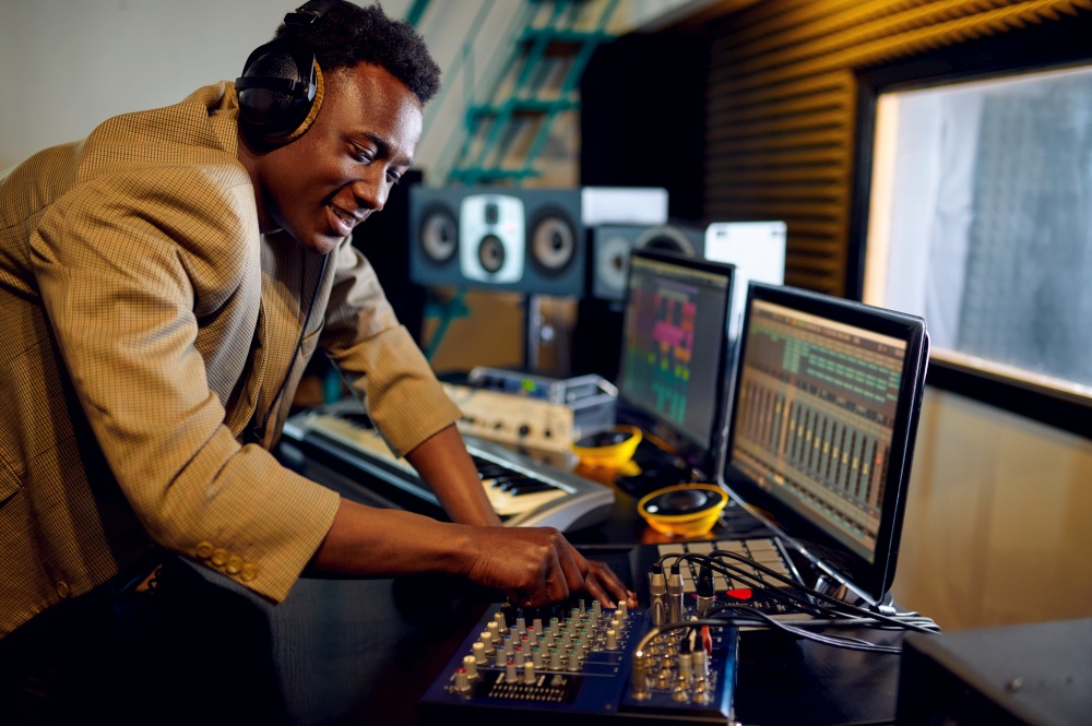 Male dj in headphones listening a record at mixing consol, recording studio interior on background. Synthesizer and audio mixer, musician workplace, creative process. Male dj listening a record, recording studio