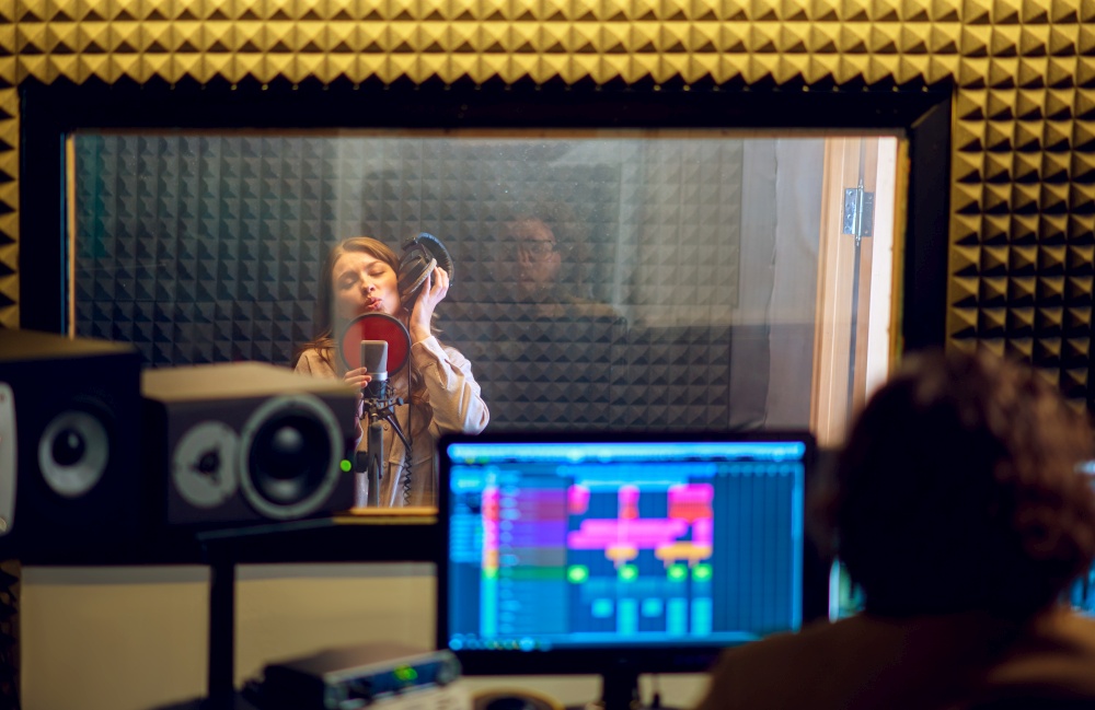 Male musician and female singer, recording studio interior on background. Synthesizer and audio mixer, musician workplace, creative process. Male musician and female singer, recording studio