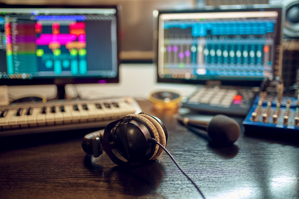 Headphones on the table, recording studio interior on background. Synthesizer, audio mixer and monitors, sound engineer workplace. Headphones on the table, recording studio interior