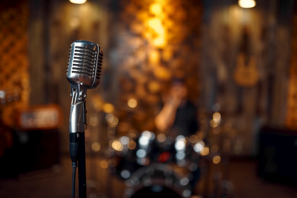 Professional chrome-plated microphone in retro style, blur garage interior on background. Rock band concert repetition, live sound performing concept. Professional chrome-plated microphone, retro style