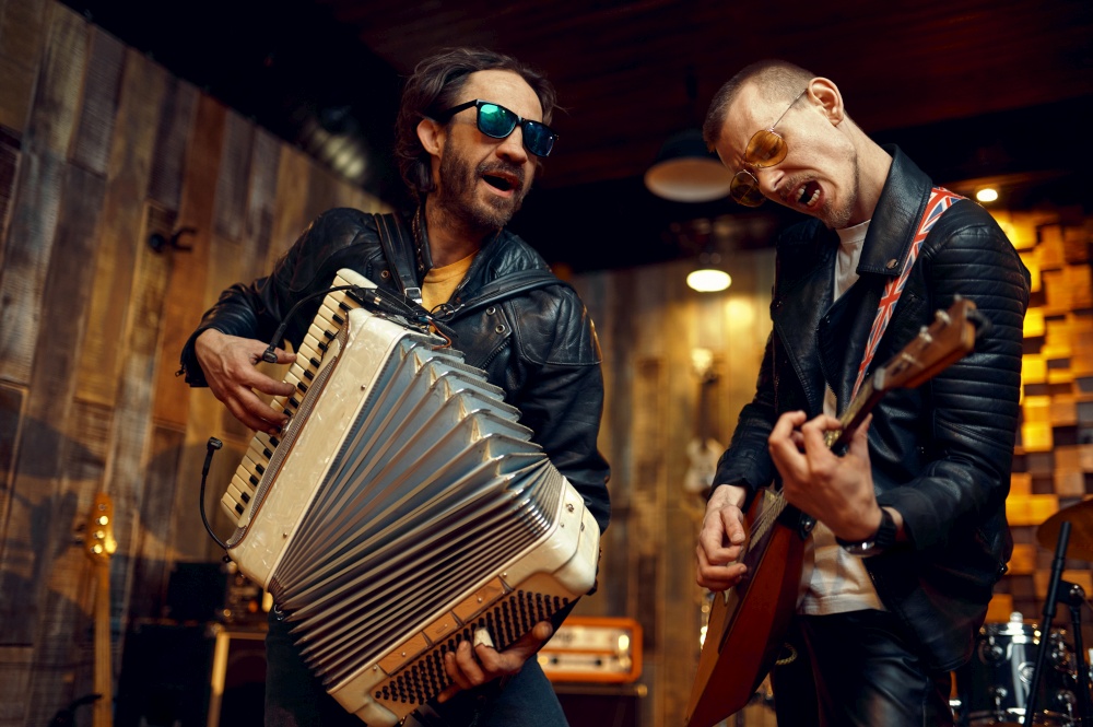 Two brutal artists with accordion and balalaika, music performing on stage. Rock band performance or repetition in garage, man with musical instrument, live sound. Artists with accordion and balalaika, rock band