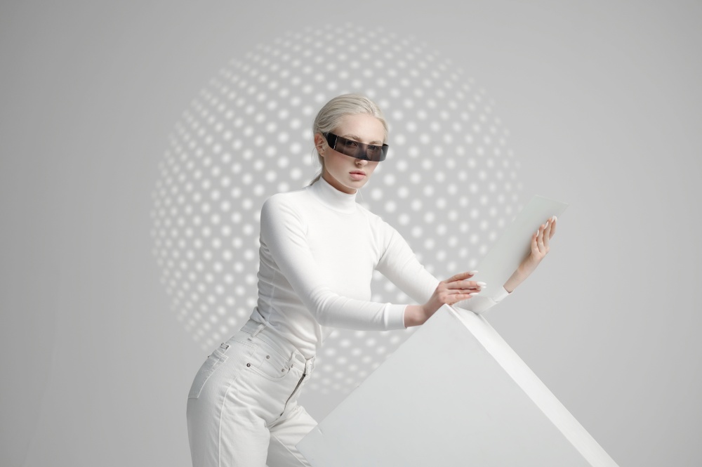 Young woman in white clothes and futuristic glasses, light grey background. Female person in virtual reality style, future technology, futurism. Woman in white clothes and futuristic glasses
