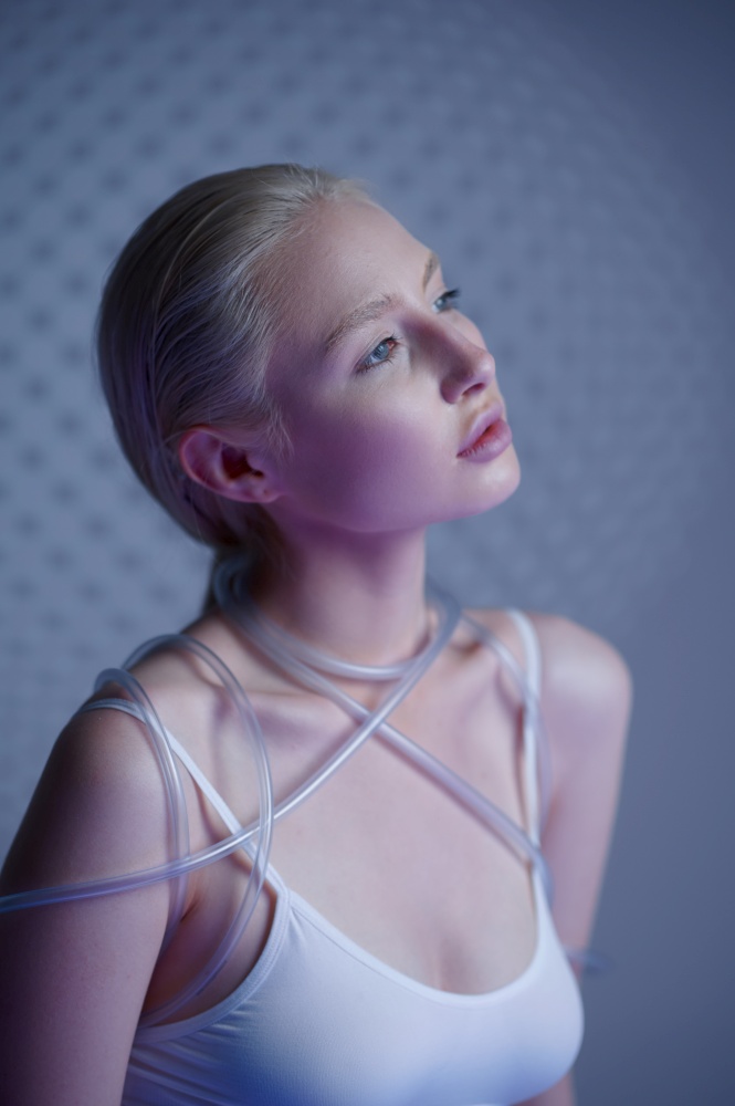 Portrait of futuristic young woman in white clothes, grey background. Female person in virtual reality style, future technology, futurism concept. Portrait of futuristic woman in white clothes