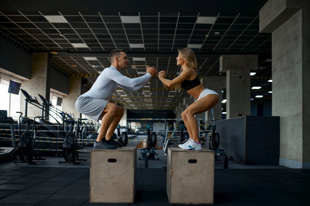Slim couple doing balance exercise on cubes in gym. Man and woman in sport club, active healthy lifestyle, physical wellness. Slim couple doing balance exercise on cubes in gym