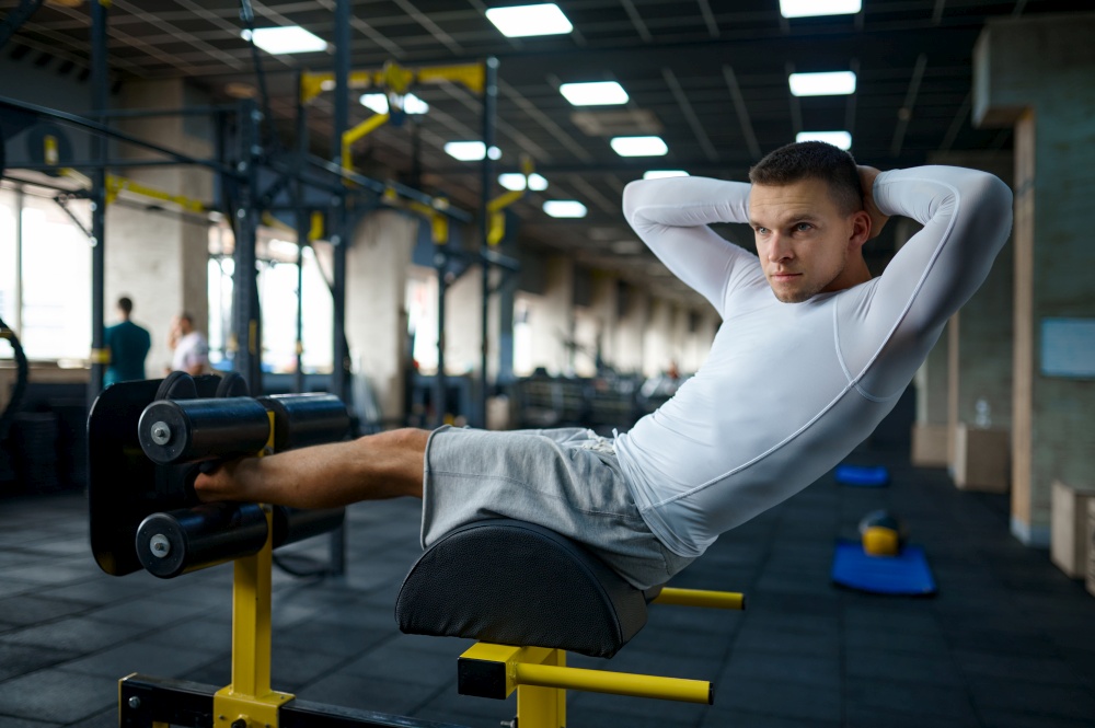 Muscular man doing abs exercise, fitness training in gym. Athletic male person on workout, sportsman in sport club, active healthy lifestyle, physical wellness. Muscular man doing abs exercise, training in gym