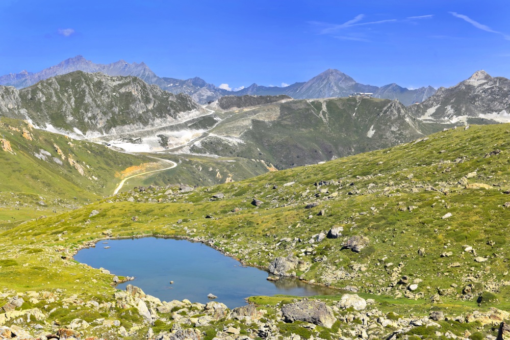 alpine mountain landscape  with a little lake in rocky meadow