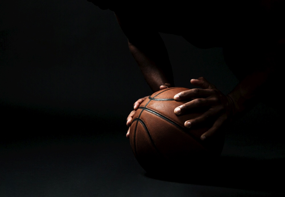 Cropped photo of afro american basketball player,  doing pushup exercise on the ball, on black background