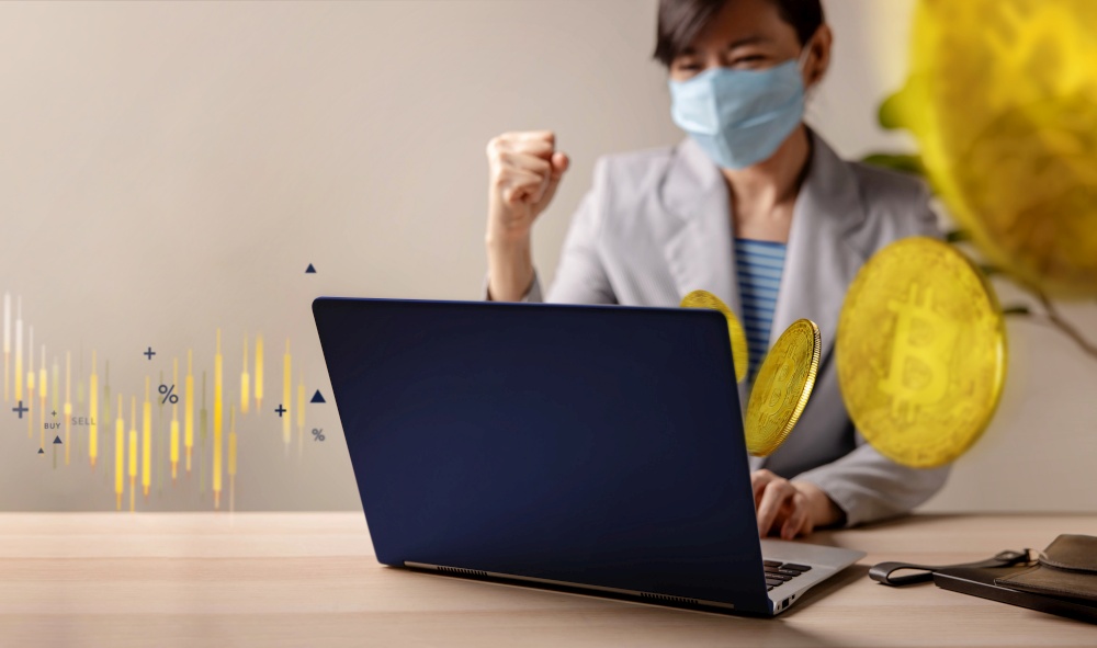 Success in Blockchain Economic Investment during Coronavirus Crisis Concept. Cheerful Young Woman Wearing Medical Mask while Using Computer Laptop to Buy and Sell Bitcoin via Cryptocurrency Exchange.