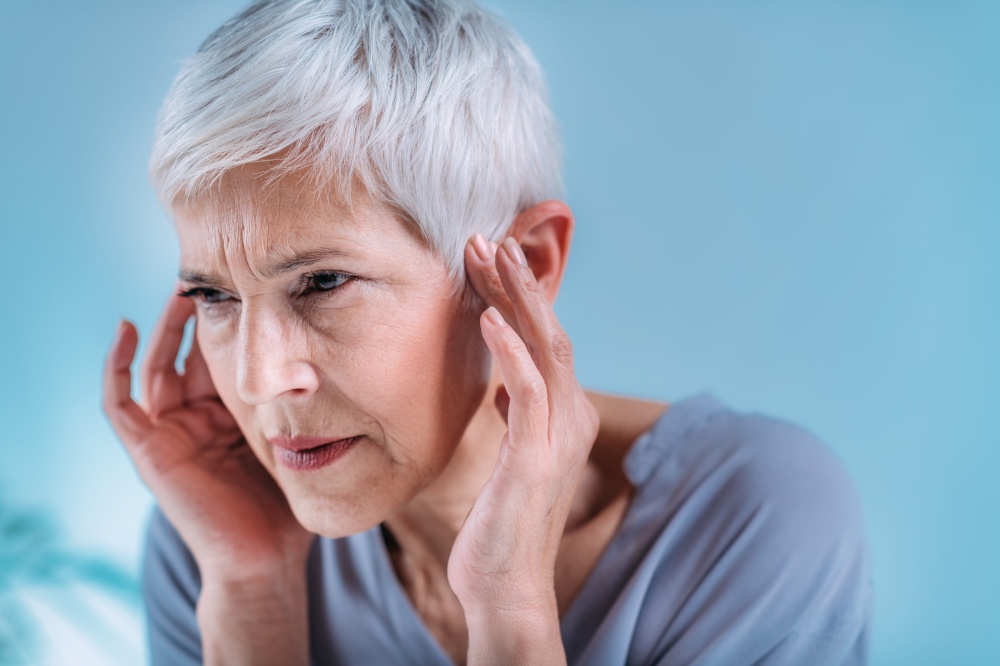 Senior woman suffering from tinnitus or ringing in her ears.. Senior Woman Suffering From Tinnitus