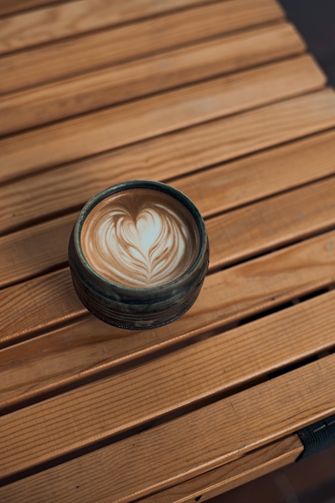 Selective focus cup of hot latte art coffee on wooden table,focus at white foam. up of hot latte art coffee on wooden