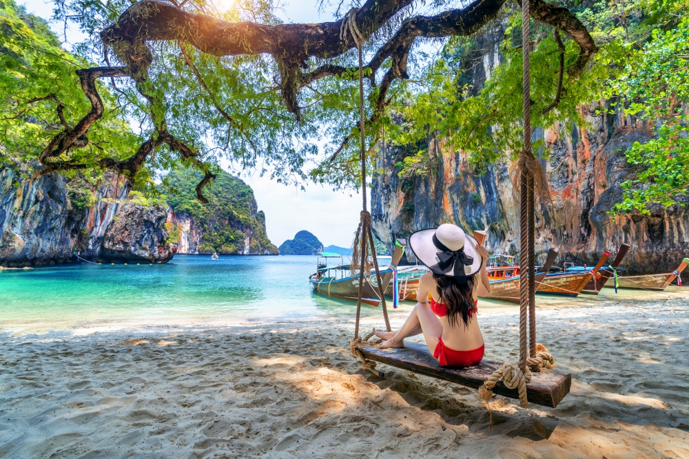 Woman in bikini relaxing on swing at Ko lao lading island, Krabi, Thailand.