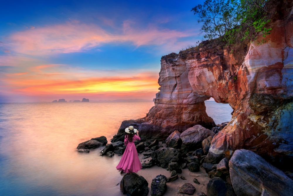 Woman standing on Laem Jamuk Khwai or Buffalo Nose Cape at sunset in Krabi, Thailand.