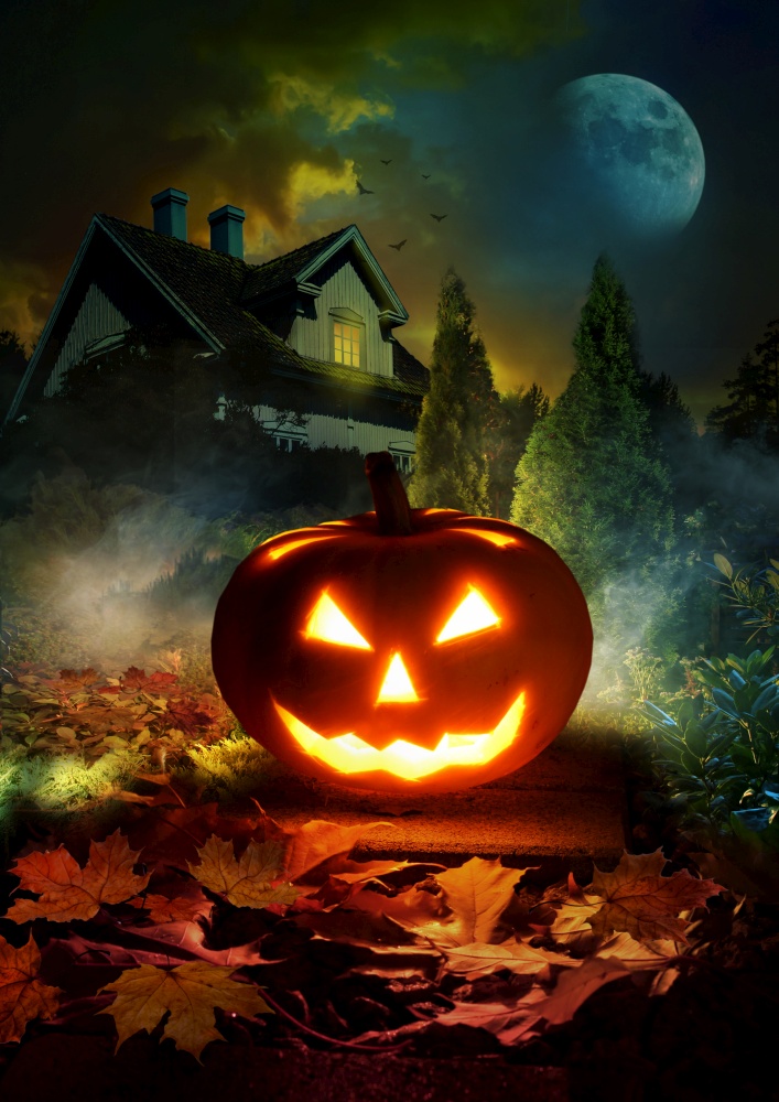 Night scene of Halloween pumpkin lantern on pathway through mystery garden to scary haunted house
