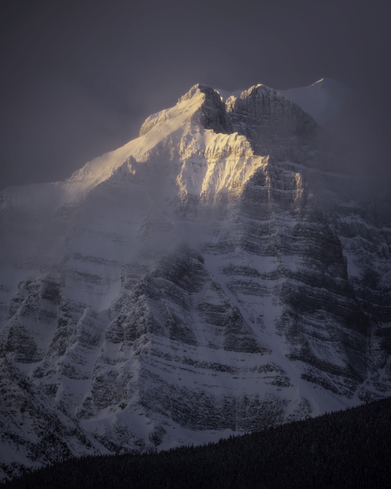 Morning light glows on a face of Mount Temple within Banff National Park during the winter.