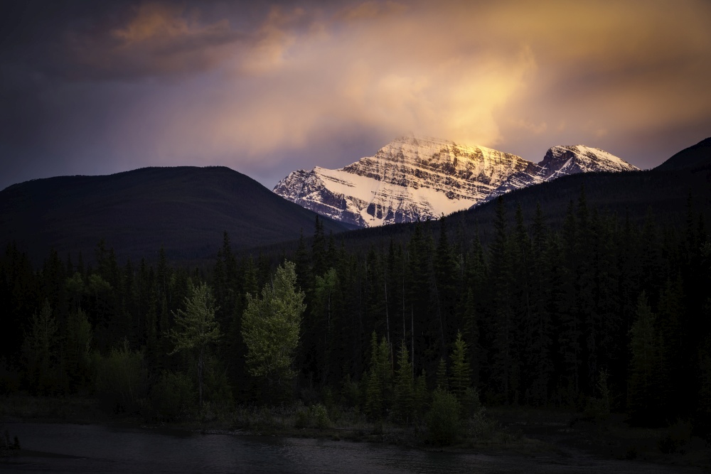 A vivid sunset along the Athabasca River as the setting sun turns the sky around Mount Edith Cavell into fire.