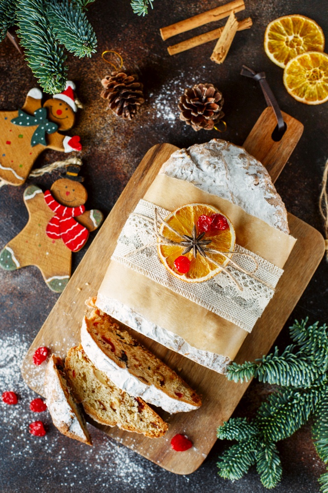 Holiday baking. Christmas cake. Flat lay Composition of stollen, spruce branches, Christmas tree decorations, cones, dry slices of oranges, berries and spices