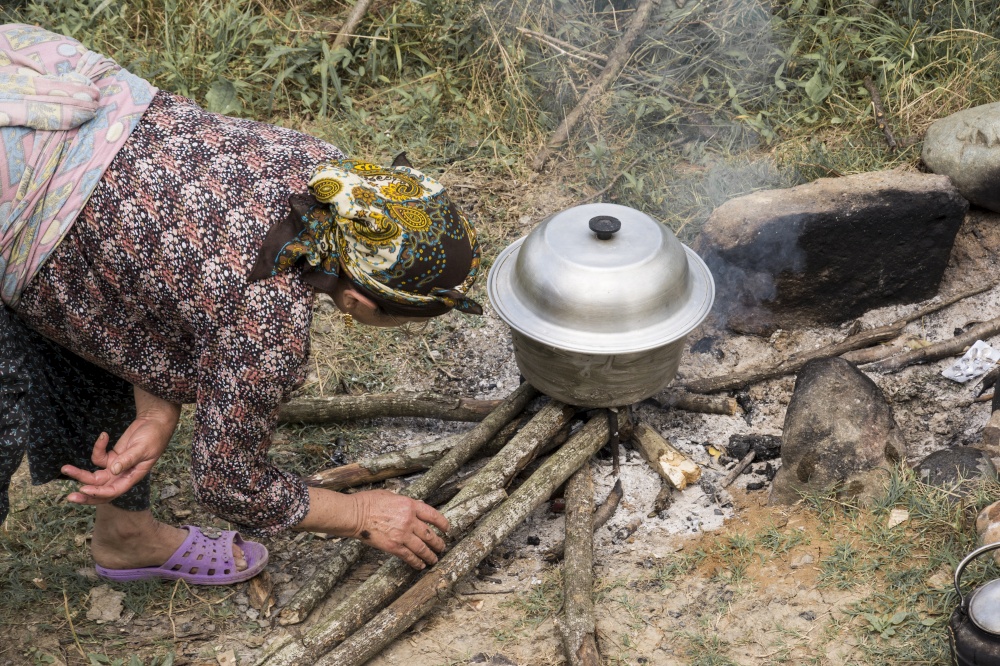 Lasak- Iranian village Muslim women in traditional clothing in outdoor area preparation food on fire, close up view. Iranian village Muslim women in traditional clothing in outdoor