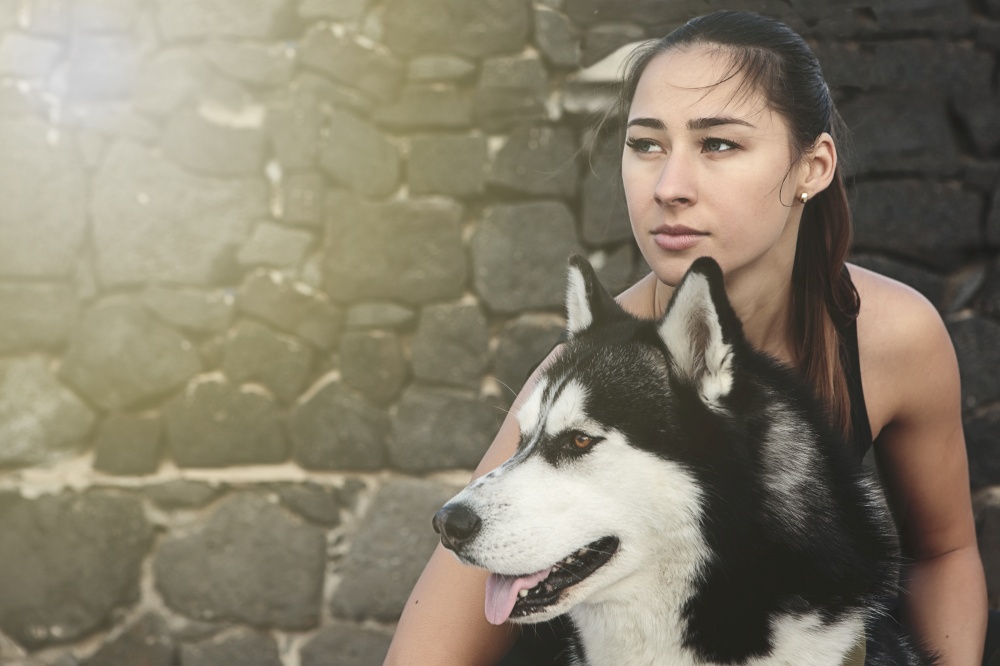 Horizontal outdoors portrait of young woman embracing her dog.. Portrait of woman with dog