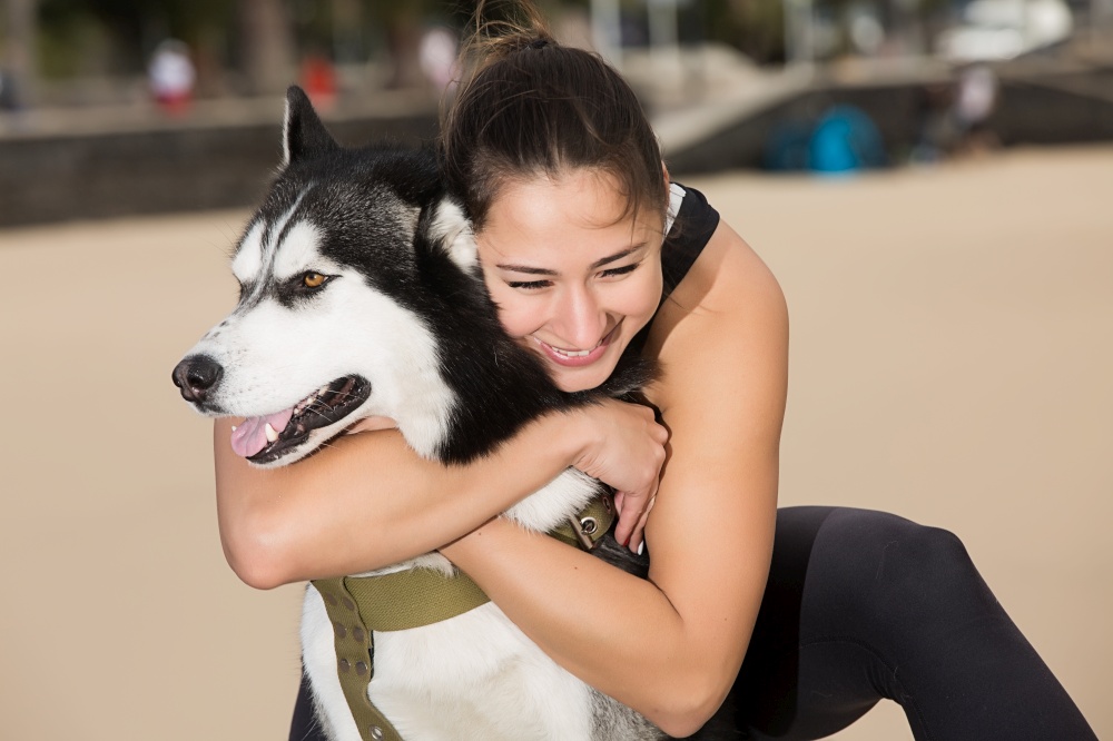 Pretty young female embracing a husky. Horizontal outdoors shot. . A dog with its owner