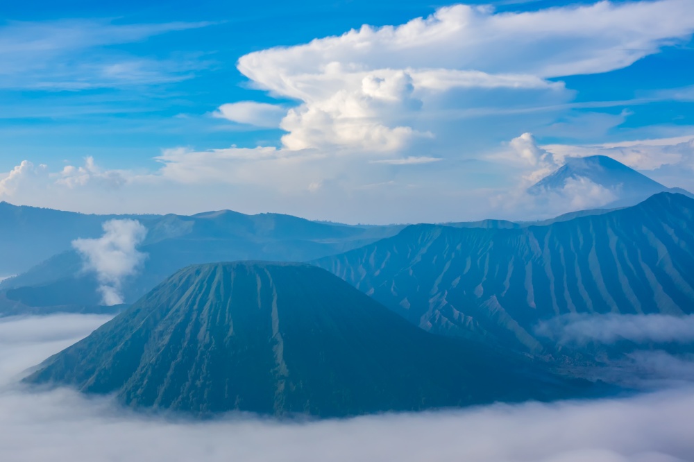 Indonesia. Java island. Morning in the Bromo Tengger Semeru National Park. Dense fog in the valley and beautiful clouds. Java Volcanoes and Morning Fog