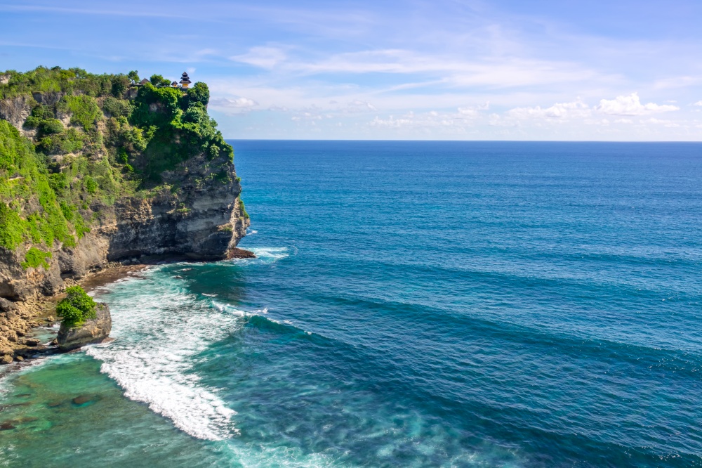 Indonesia. A high and rocky coast of the ocean. Day. A small traditional temple on top of a cliff. Temple on the Coastal Rock