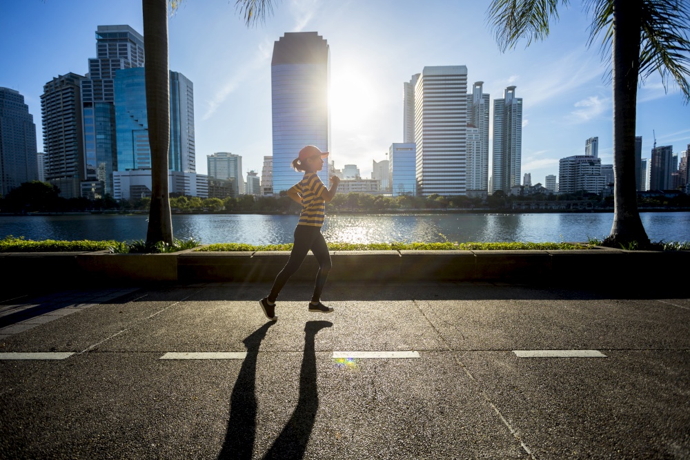 Beautiful woman running in city during sunrise