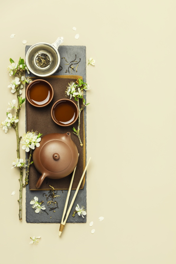 Asian Tea set on stone slate board, ceramic teapot, cups, dried tea and spring branches, tea ceremony, flat lay