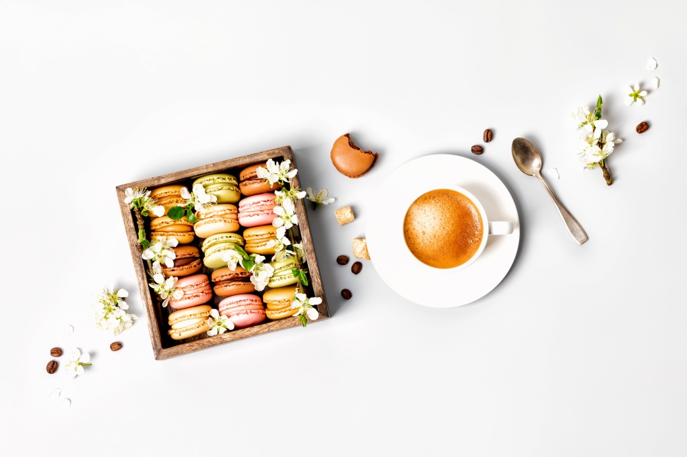 Macaroons in wooden box with spring flowers and cup of coffee flat lay. Macaroons in wooden box with spring flowers and cup of coffee