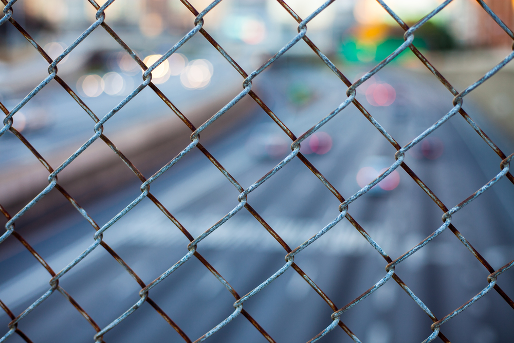 City skyline through the wire mesh fence. Abstract blurred cityscape background