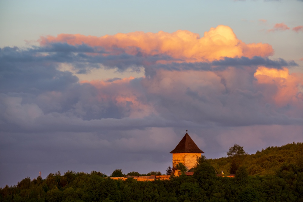 Pyatnychany tower (defense structure, 15th century) on evening twilight forest hill slope, Lviv Region, Ukraine.