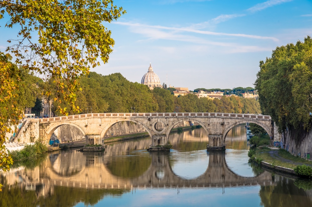 ROME, ITALY - CIRCA AUGUST 2020: Bridge on Tiber river with Vatican Basilica cupola in background and sunrise light.