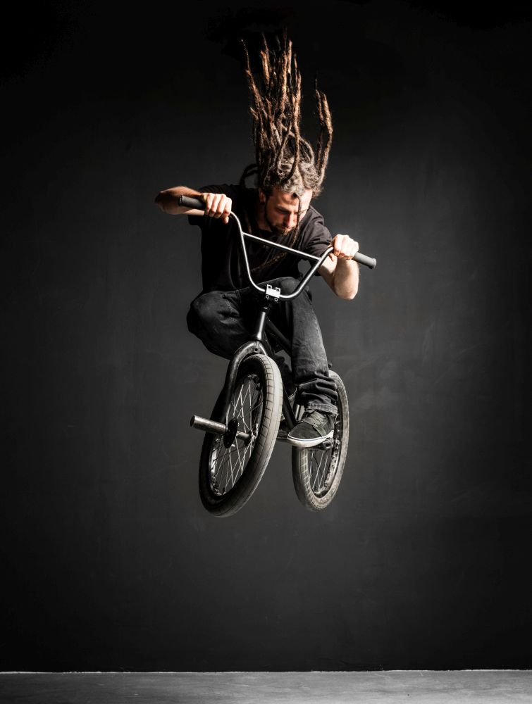 Young man with dreadlocks jumping on his BMX bike. Extreme sports.. Young man with dreadlocks jumping on his BMX bike.