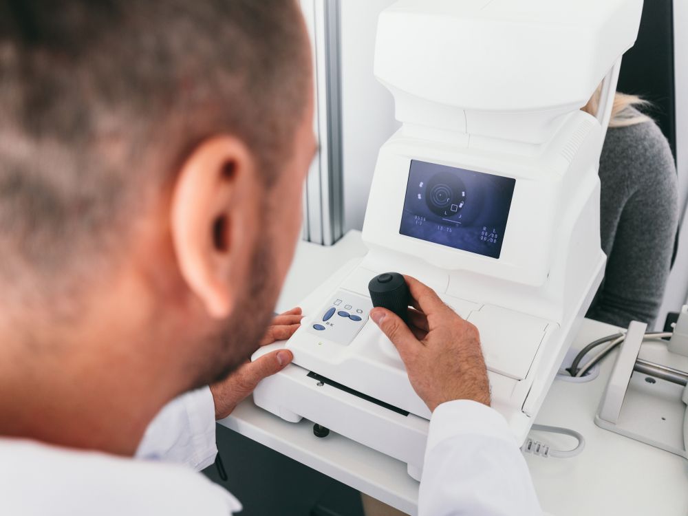 Optician checking his patient&rsquo;s eye on a machine. Medical vision examination.. Optician checking his patient&rsquo;s eye on a machine.