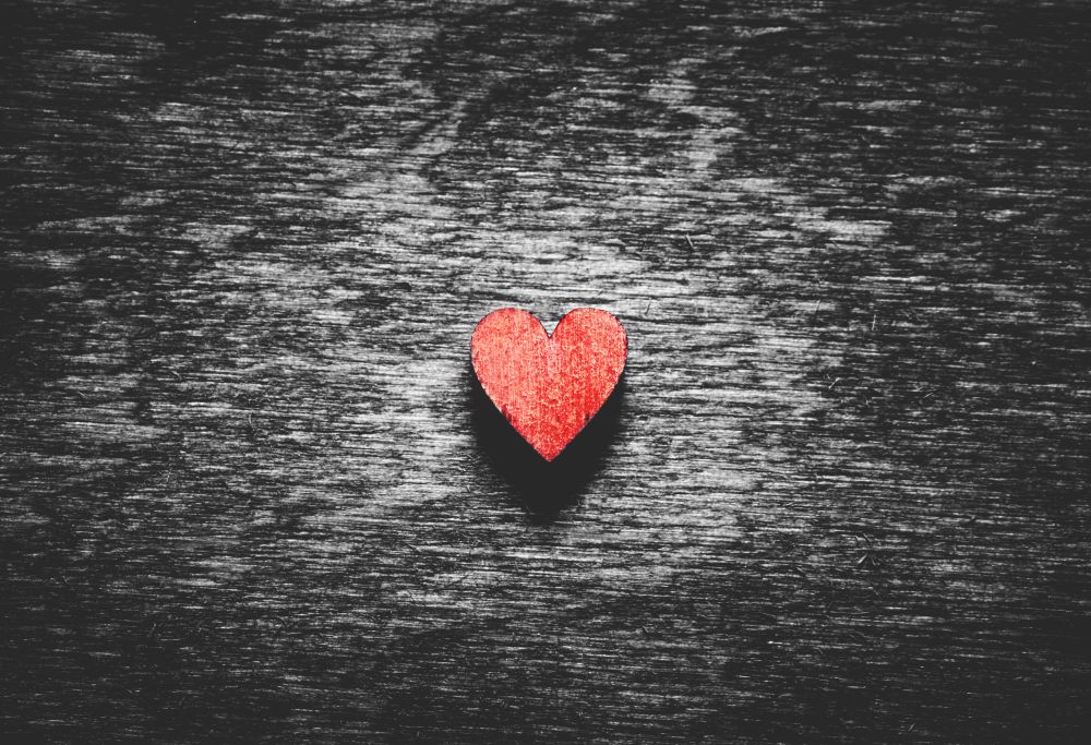 Red wooden heart on black wooden background. Love symbol. Valentine&rsquo;s Day.. Red heart on black wooden background