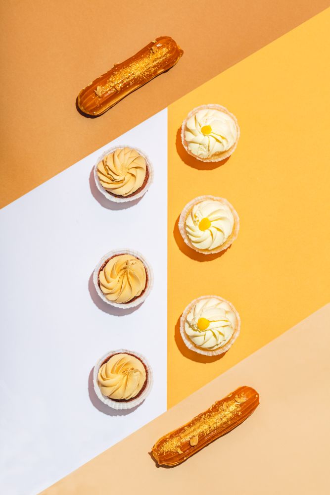 Flat lay composition of sweet desserts. Bright, warm colors. Cupcakes and eclairs, pastry.. Flat lay composition of sweet desserts