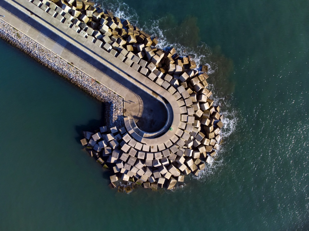 Aerial view of cement blocks protecting the shore from the waves in the port of Luanco in Asturias, Spain.