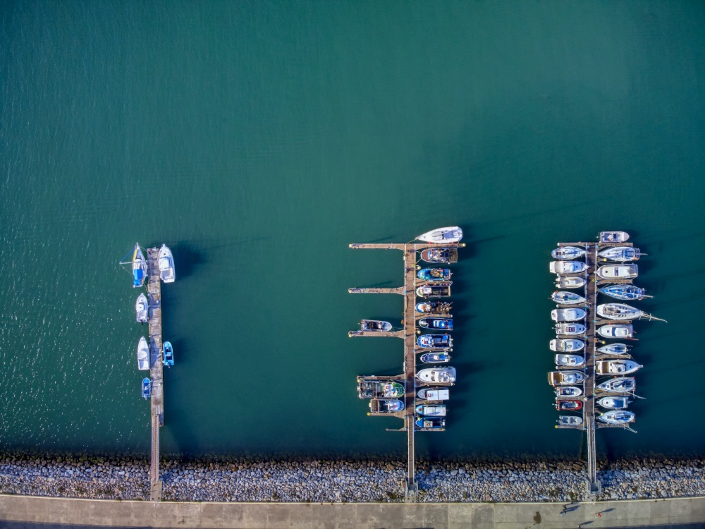 Panoramic Aerial view on boats moored in the pier, drone shot directly above. Luanco in Asturias, Spain.