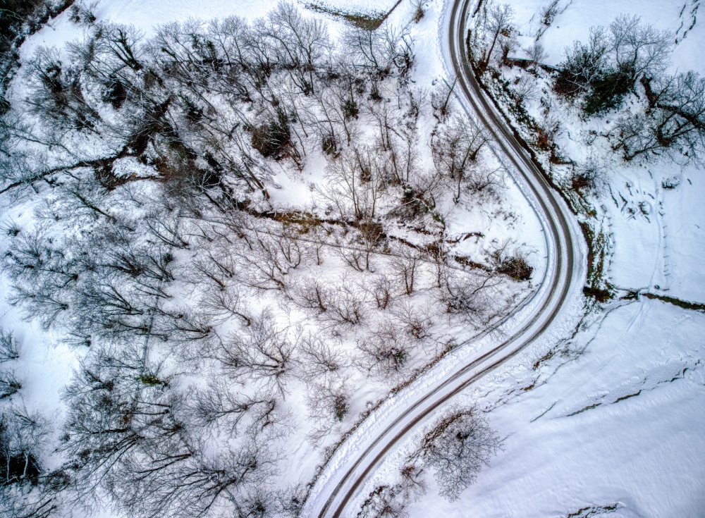 Aerial view of winding road through snowy landscape in Asturias mountains in Spain. Winter time.
