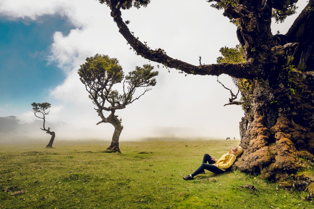 Woman resting near an Ancient tree and enjoying the view