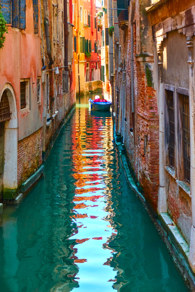 Colorful smalll venetian canal with moored boat, Venice, Italy